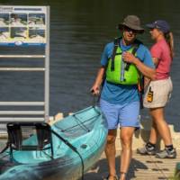two people carrying a kayak up a dock